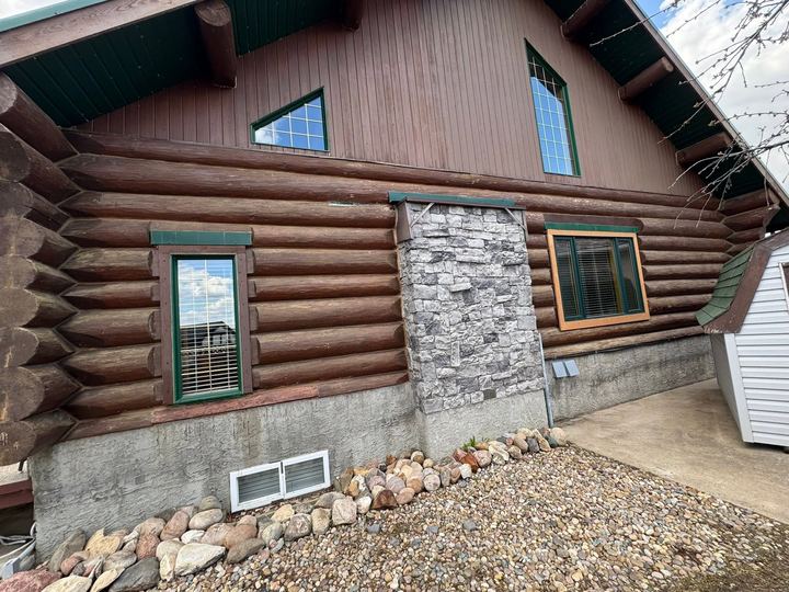 Log home with dark failing stain before restoration
